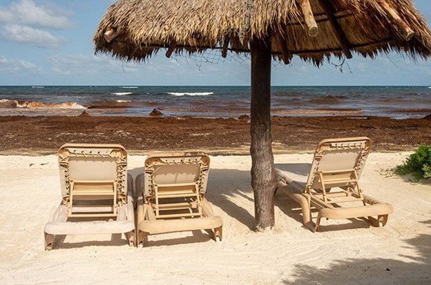 Foto de sillas de playa vacías en la playa frente al mar Caribe 