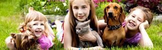 Picture of three small children holding two dogs and a cat.