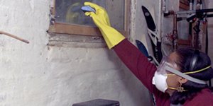  Persona con ropa protectora limpiando una casa dañada.