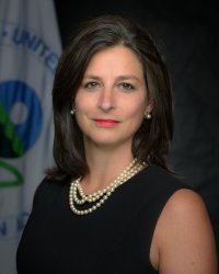 Imagen de la directora de la Oficina de Salud Ambiental Infantil, Grace Robiou, con una bandera blanca que contiene el logotipo de la Agencia de Protección Ambiental de EE. UU., EPA.