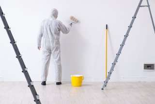 Persona pintando mientras usa un uniforme de protección desechable